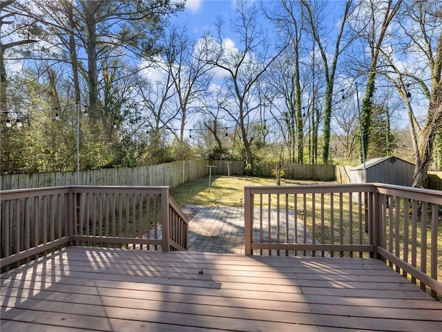 wooden terrace featuring a fenced backyard, an outbuilding, and a shed