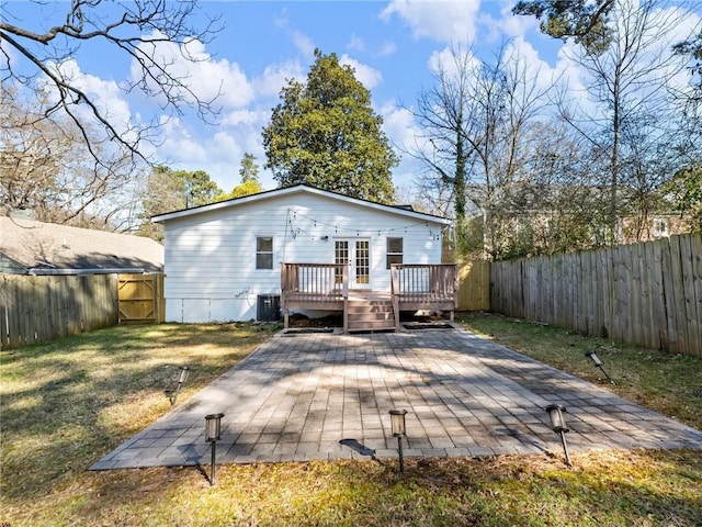 rear view of house featuring a lawn, a patio area, a deck, cooling unit, and a fenced backyard