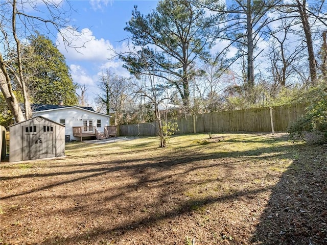 view of yard featuring an outbuilding, a fenced backyard, a deck, and a storage unit