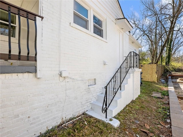 view of property exterior with brick siding and fence