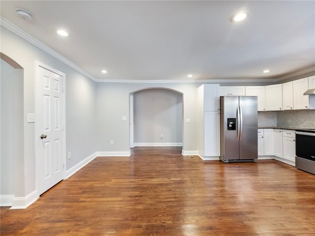 kitchen featuring arched walkways, white cabinets, dark wood-style floors, appliances with stainless steel finishes, and crown molding