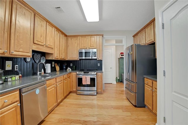 125 Rabbits Run, Fayetteville, GA 30215 - kitchen featuring stainless steel appliances, a sink, light wood-style floors, backsplash, and dark countertops