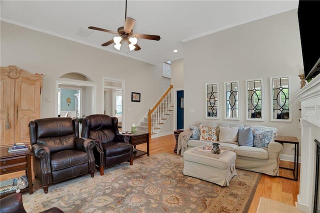 125 Rabbits Run, Fayetteville, GA 30215 - living room featuring a fireplace, stairs, a ceiling fan, ornamental molding, and light wood-style flooring