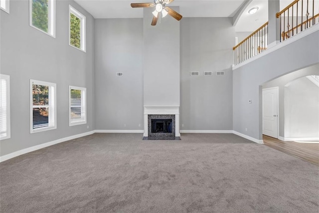 unfurnished living room with a towering ceiling, carpet floors, and ceiling fan