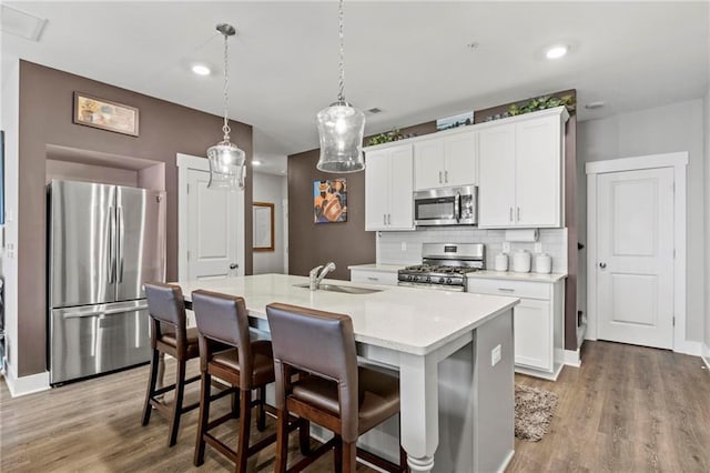 kitchen with stainless steel appliances, a sink, light wood-style flooring, backsplash, and recessed lighting