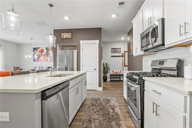 kitchen with appliances with stainless steel finishes, a sink, light wood finished floors, backsplash, and recessed lighting