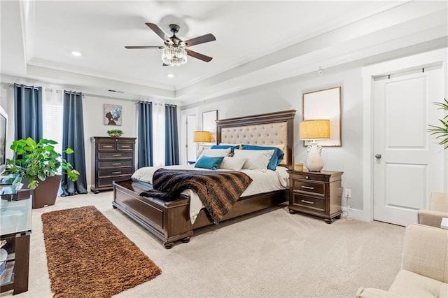bedroom with light carpet, ornamental molding, a tray ceiling, baseboards, and a ceiling fan