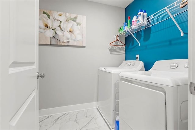 clothes washing area with separate washer and dryer, marble finish flooring, and baseboards