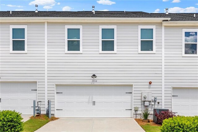 view of home's exterior with an attached garage, cooling unit, and concrete driveway