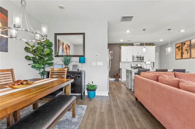 living room with a chandelier, wood finished floors, recessed lighting, and baseboards