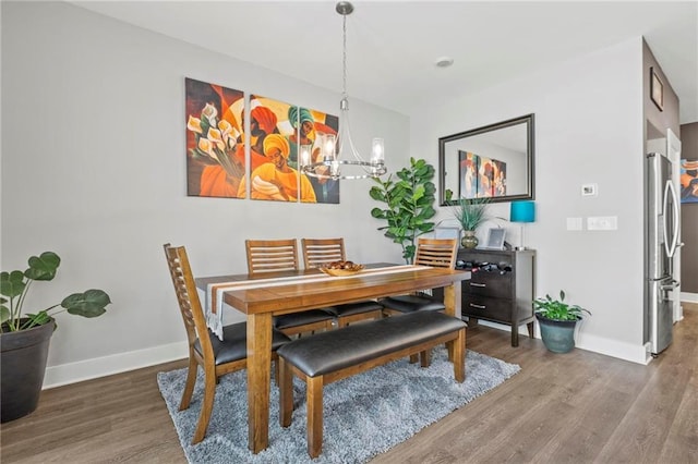 dining room featuring a chandelier, wood finished floors, and baseboards