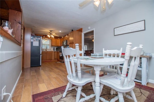 dining area with light hardwood / wood-style floors and ceiling fan