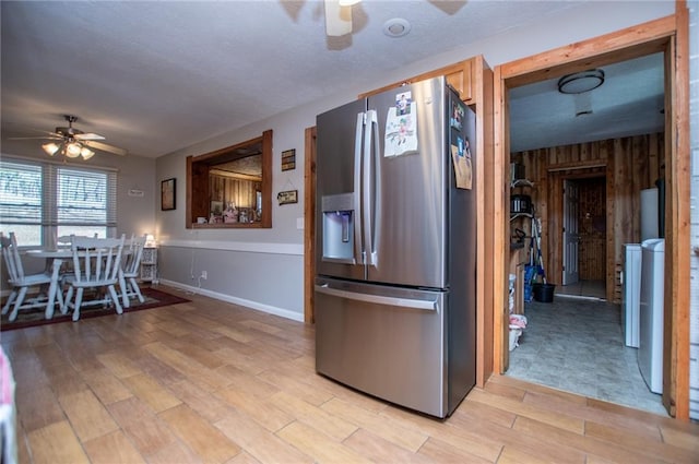 kitchen featuring light hardwood / wood-style flooring, stainless steel fridge, wooden walls, and ceiling fan