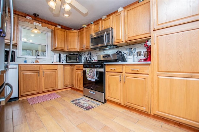 kitchen with sink, backsplash, hanging light fixtures, ceiling fan, and stainless steel appliances