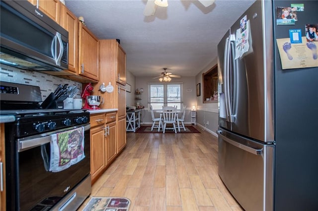 kitchen featuring decorative backsplash, light hardwood / wood-style floors, ceiling fan, and appliances with stainless steel finishes