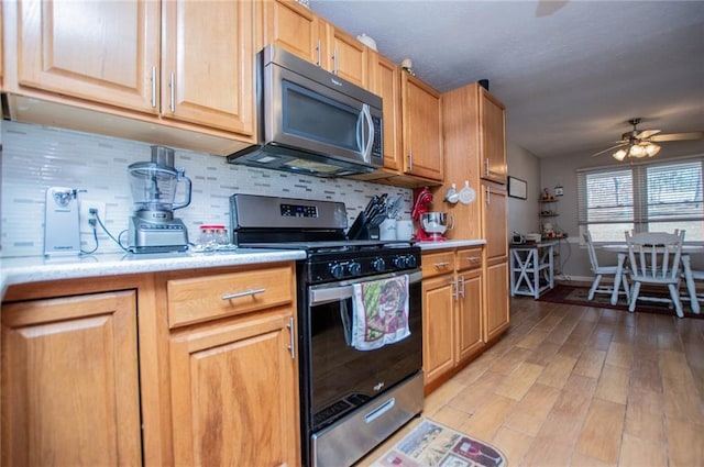 kitchen featuring tasteful backsplash, ceiling fan, appliances with stainless steel finishes, and light hardwood / wood-style flooring