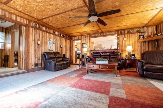 living room featuring tile patterned flooring, ceiling fan, and wood walls