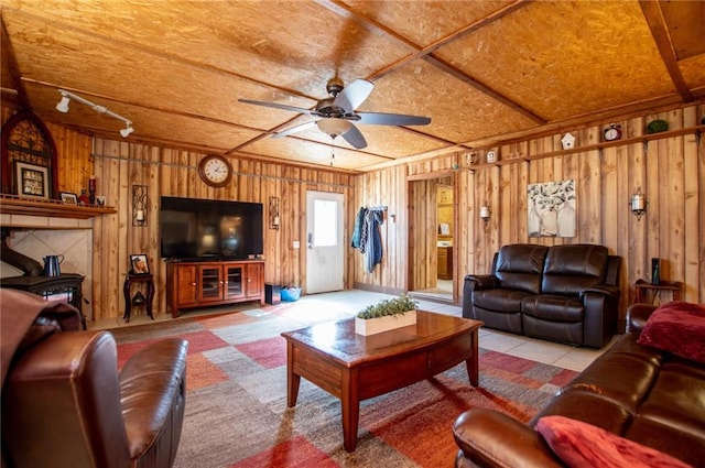 living room featuring track lighting, ceiling fan, and wood walls