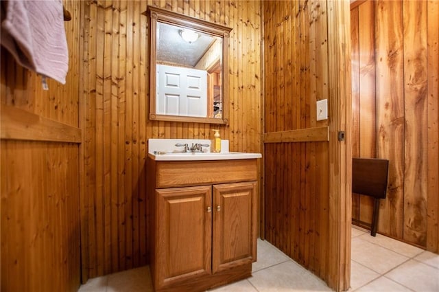 bathroom with tile patterned flooring, vanity, and wood walls