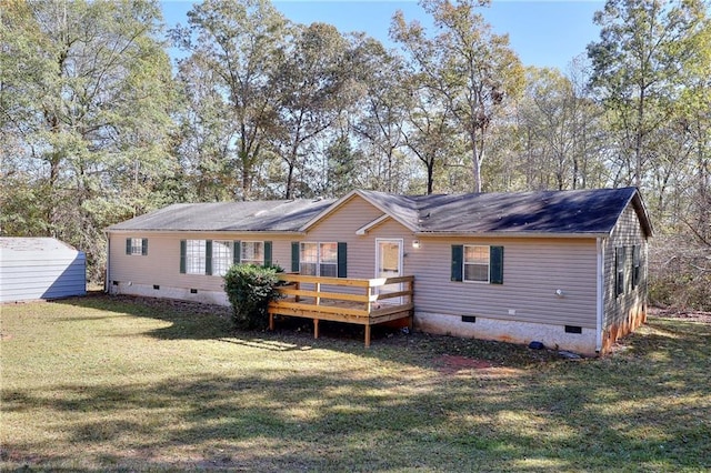 rear view of property featuring a storage unit, a yard, and a wooden deck