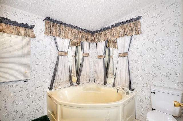 bathroom featuring a textured ceiling, a bathtub, and toilet