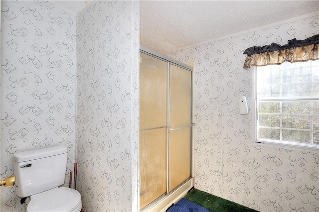 bathroom featuring toilet, a textured ceiling, and a shower with shower door