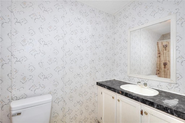 bathroom featuring toilet, vanity, and a shower with curtain