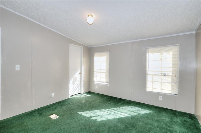 empty room featuring dark carpet, a textured ceiling, ornamental molding, and vaulted ceiling