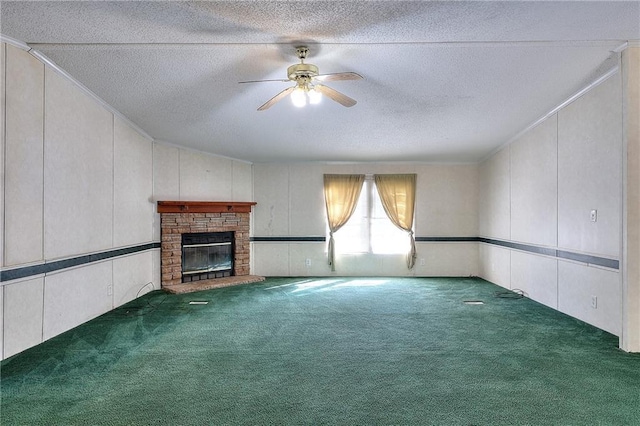 unfurnished living room with a textured ceiling, ceiling fan, a fireplace, and dark carpet