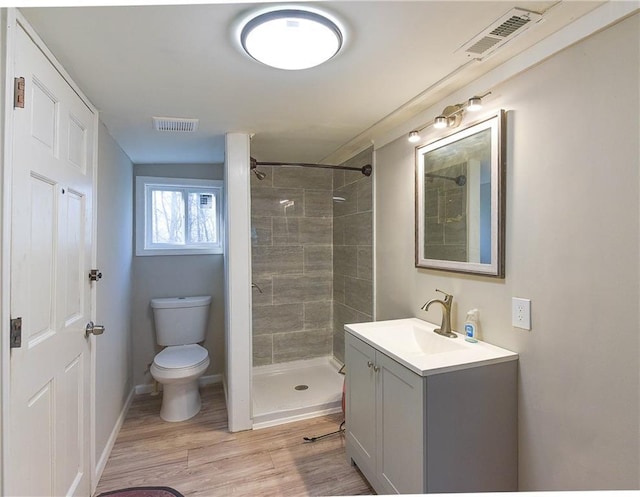 full bath with toilet, visible vents, wood finished floors, and tiled shower