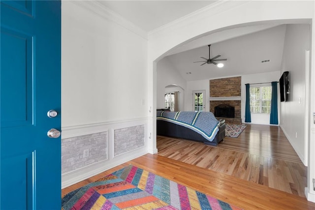 foyer entrance featuring a fireplace, wood finished floors, a ceiling fan, and ornamental molding