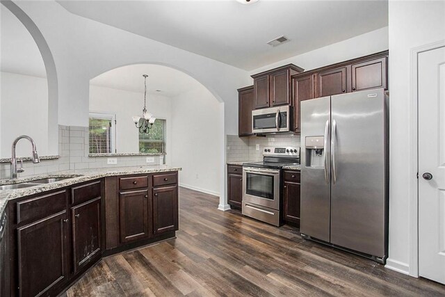 kitchen with stainless steel appliances, a notable chandelier, sink, dark hardwood / wood-style floors, and pendant lighting