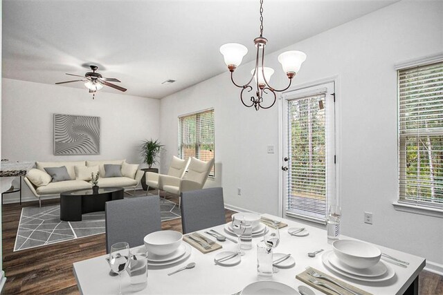 dining area with ceiling fan with notable chandelier, dark wood-type flooring, and a healthy amount of sunlight