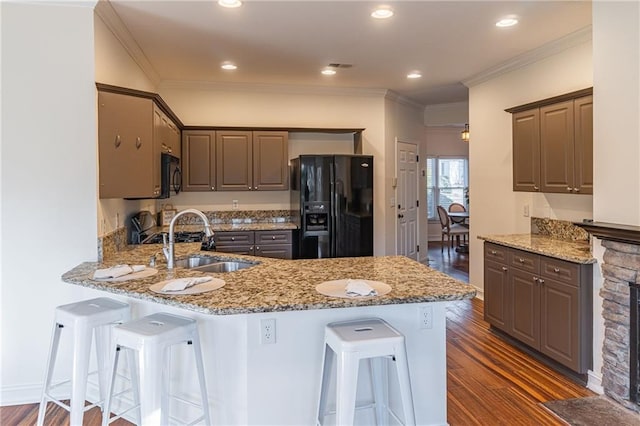 kitchen featuring a kitchen breakfast bar, black appliances, light stone counters, and kitchen peninsula