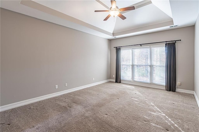 carpeted spare room with ceiling fan and a raised ceiling