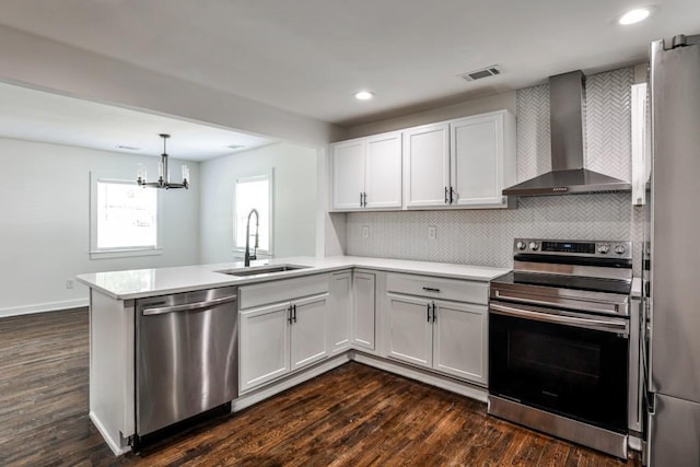 2195 Penelope St NW, Atlanta, GA 30314 - kitchen featuring wall chimney range hood, appliances with stainless steel finishes, an inviting chandelier, a sink, and a peninsula