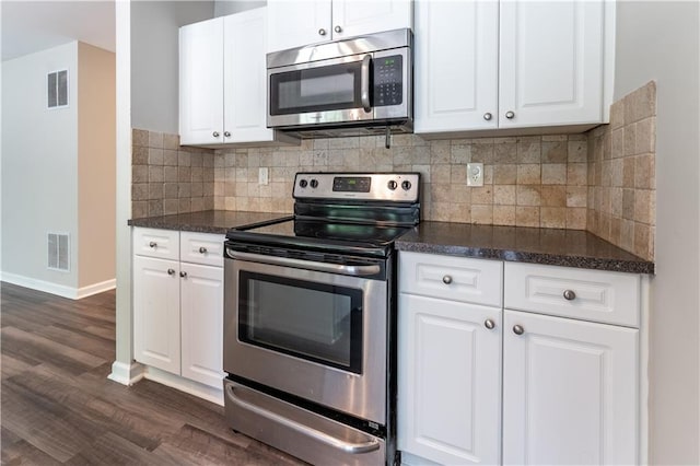 kitchen with dark wood finished floors, dark countertops, visible vents, and stainless steel appliances