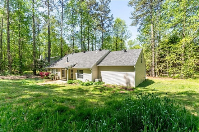 back of house featuring a yard and roof with shingles