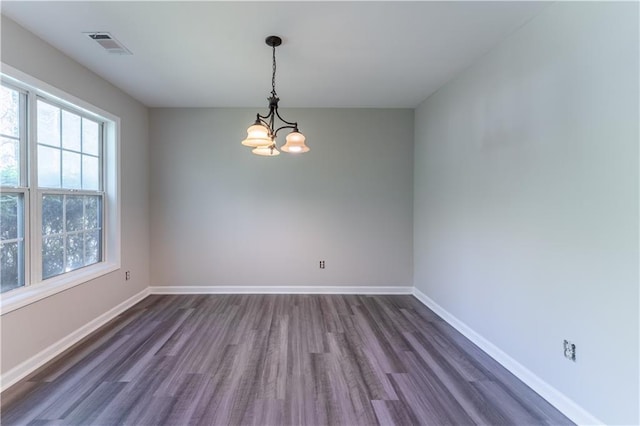 spare room with baseboards, visible vents, an inviting chandelier, and dark wood-type flooring