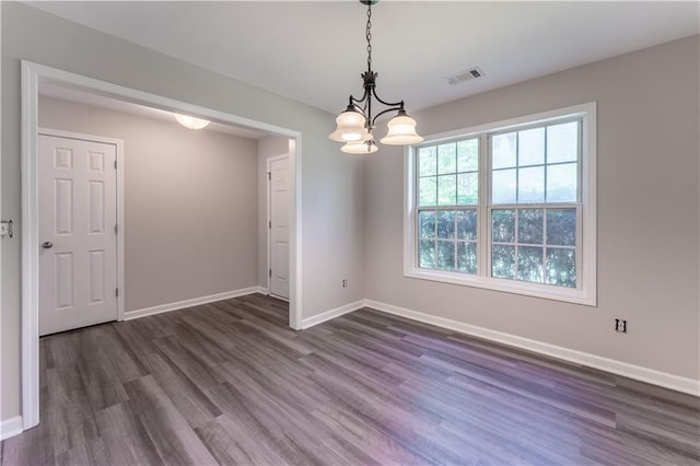 empty room with dark wood-type flooring, a chandelier, visible vents, and baseboards