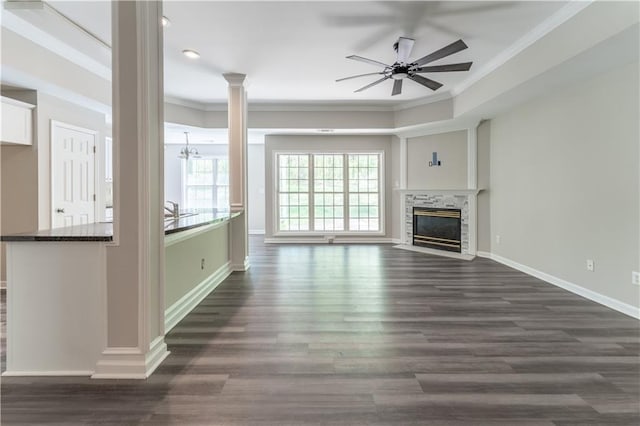 unfurnished living room with dark wood finished floors, crown molding, baseboards, decorative columns, and ceiling fan