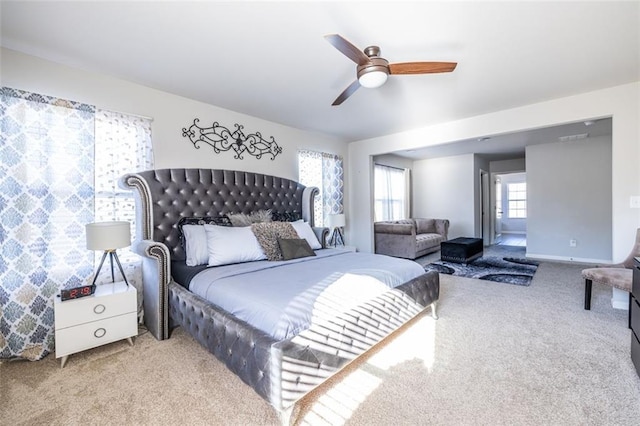 bedroom with multiple windows, ceiling fan, and light carpet