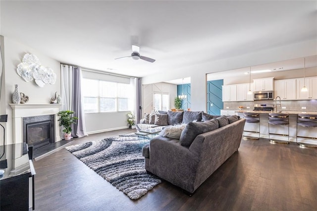 living room featuring ceiling fan, dark wood-type flooring, and sink