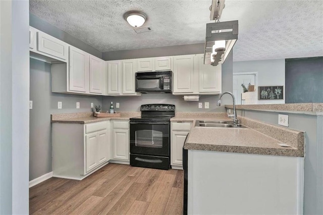 2551 Luther Bailey Rd, Senoia, GA 30276 - kitchen featuring black appliances, light wood-style floors, a peninsula, a textured ceiling, and white cabinets