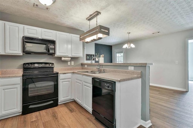 2551 Luther Bailey Rd, Senoia, GA 30276 - kitchen with black appliances, a textured ceiling, light wood-style floors, a peninsula, and white cabinets
