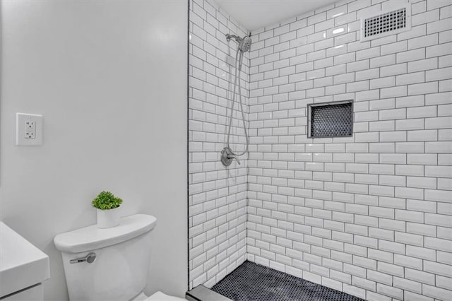 full bathroom featuring toilet, visible vents, and a tile shower