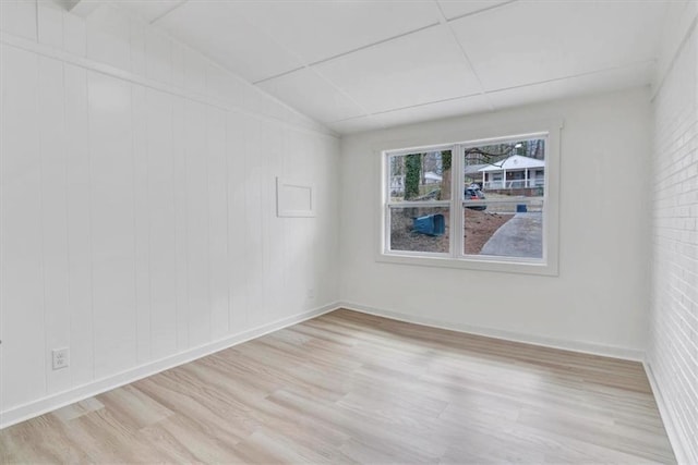 unfurnished room featuring lofted ceiling, light wood finished floors, and baseboards