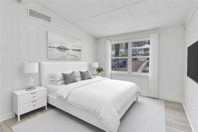 bedroom featuring vaulted ceiling, visible vents, baseboards, and wood finished floors