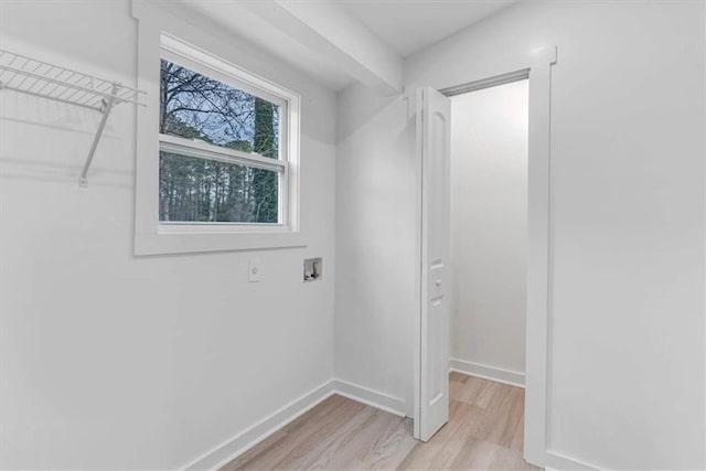 clothes washing area with light wood finished floors, baseboards, and washer hookup