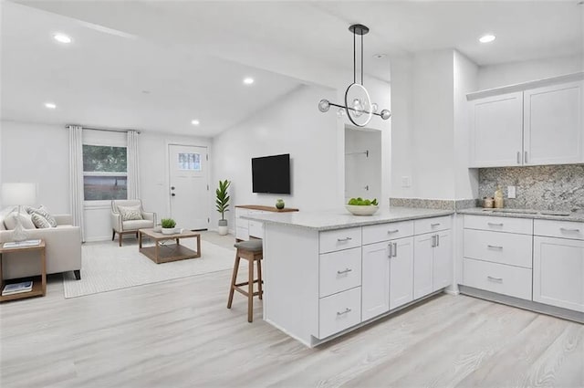 kitchen with a peninsula, lofted ceiling with beams, decorative backsplash, white cabinets, and open floor plan